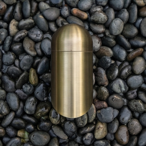 Close-up of a brass landscape lighting fixture, showcasing its elegant design and construction against a background of dark stones.