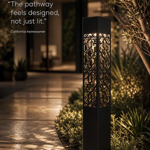 A black geometric bollard light with an intricate cut-out pattern casting shadow designs on a wet pathway at night.