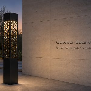 Black square outdoor bollard light with intricate geometric patterned cutouts, illuminated from within, standing on a concrete pathway beside a textured concrete wall at dusk.